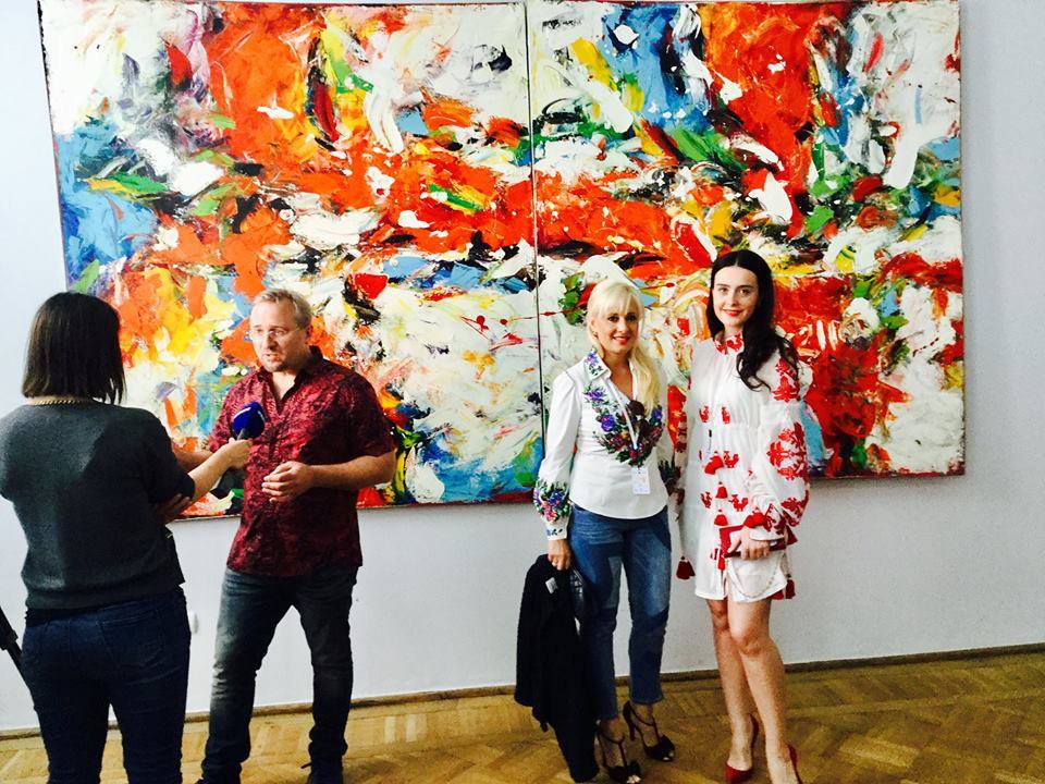Press interview in front of a monumental canvas at an exhibition opening